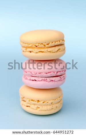 Picture of three sweet colorful macaroons on blue table background.