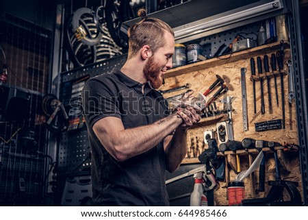 Bearded male bicycle mechanic cleans his arms after bike service manual in a workshop.