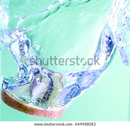 orange  slice falling in water, leaving splashes and bubbles