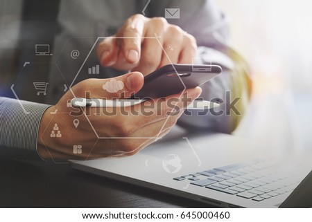 close up of businessman working with mobile phone and stylus pen and laptop computer on wooden desk in modern office with virtual icon diagram