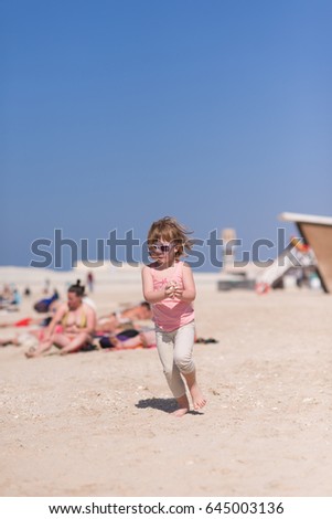 happy little girl at the seaside in the summer.Adorable little girl at beach during summer vacation. Happy baby with sunglasses by the sea or ocean