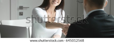 Friendly smiling businessman and businesswoman handshaking over the office desk after pleasant talk and effective negotiation, good relationships. Horizontal photo banner for website header design 
