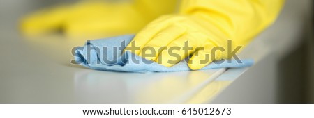 Close up of hands in rubber protective yellow gloves cleaning the white surface with a rag. Home, housekeeping concept. Horizontal photo banner for website header design 