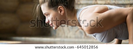 Closeup of young happy attractive woman practicing yoga, doing four limbed staff, push ups or press ups exercise. Horizontal photo banner for website header design with copy space for text 