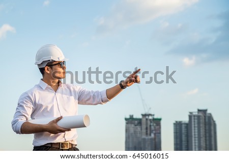Asian young businessman pointing a finger forward on bright sky background, future business concept, copy space on Right side.
