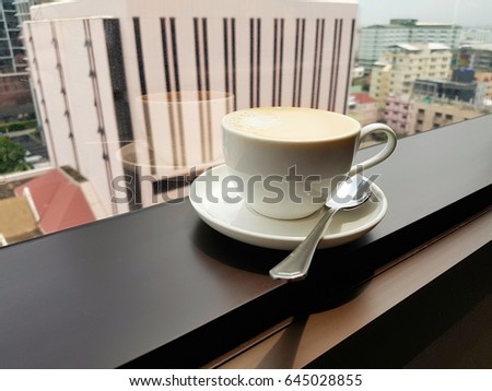 Cup of coffee in front of window with blurred city view