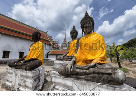 A picture of three buddha replica wrapped in golden clothes situate in the temple