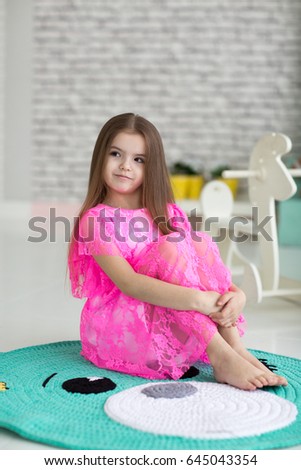 Pretty little girl in pink dress in studio