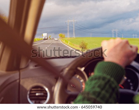 Car rides on the country road. The driver's hands are on the handlebars. Inside view