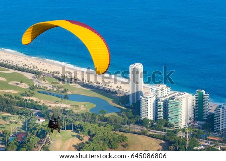 Practicing paragliding near the beach. / Paragliding./ View of the beach and the city.