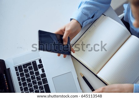 Laptop, notebook, pen, girl's hand holds the phone                               