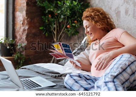 Radiant pregnant woman looking at colour palette