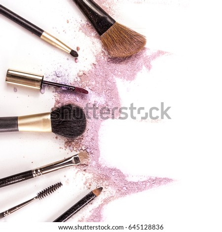 Makeup brushes, lip gloss and pencil on white background, with traces of powder and blush forming a frame. A square template for a makeup artist's business card or flyer design, with copyspace