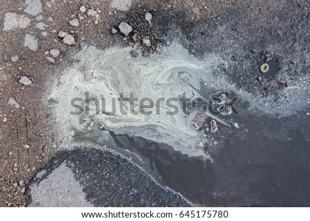 Dirty puddle on the asphalt with white foam