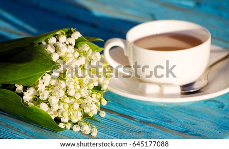 Hot tea in a white cup with a bouquet of flowers on a wooden background