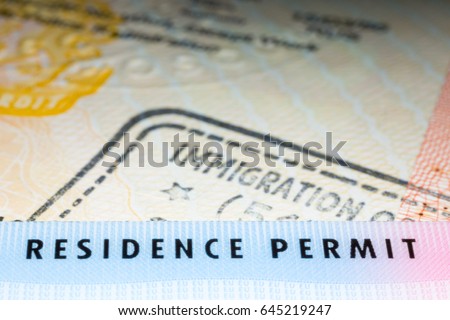 Immigration concept image. Residence permit card over immigration stamp on UK student visa in passport. Selective focus Royalty-Free Stock Photo #645219247