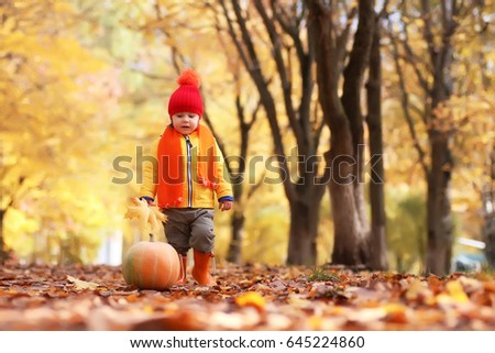 kid in autumn park with pumpkin play and having fun