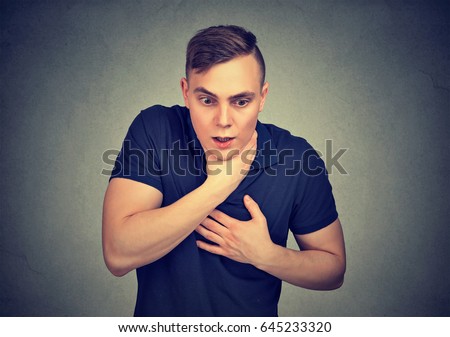 Young man having asthma attack or choking suffering from respiration problems isolated on gray background   Royalty-Free Stock Photo #645233320