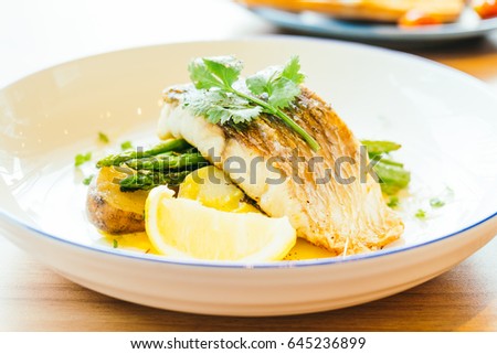 Grilled Barramundi or pangasius fish and meat steak with vegetable and lemon in plate - Healthy food style