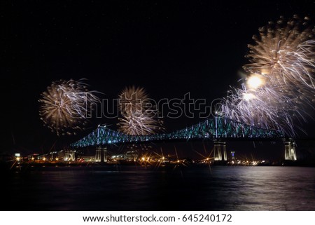 Colorful fireworks explode over bridge, reflection in water. Montreal’s 375th anniversary. luminous colorful interactive Jacques Cartier Bridge. Bridge panoramic colorful silhouette by night.