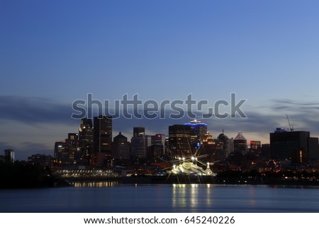 Montreal Downtown Panorama at sunset. Montreal reflected on the river at dusk with city lights and urban buildings. Montreal over river at sunset with city lights. Montreal reflected in water. 