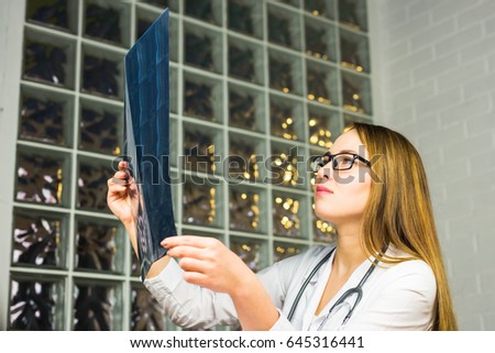 Portrait of intellectual woman healthcare personnel with white labcoat, looking at full body x-ray radiographic image, hospital clinic background. Radiology department