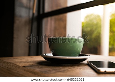A coffee cup with the smart phone on the wooden table
