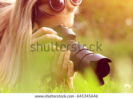Female photographer take photo on meadow.