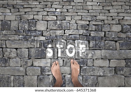 Barefoot man standing on rocky floor with written stop sign message on the floor, point of view perspective. Royalty-Free Stock Photo #645371368