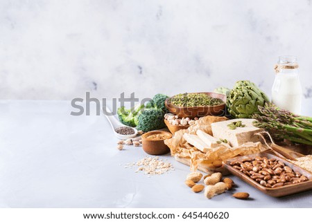 Assortment of healthy vegan protein source and body building food. Tofu soy milk beans asparagus broccoli artichokes almond peanut pumpkin chia flax seeds quinoa oat meal. Copy space background