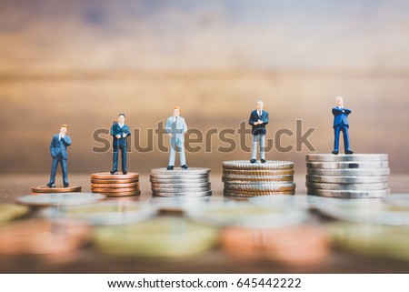 Miniature people businessman standing on money with  wooden background