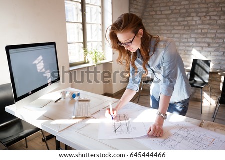 Female designer in office working on architects project Royalty-Free Stock Photo #645444466
