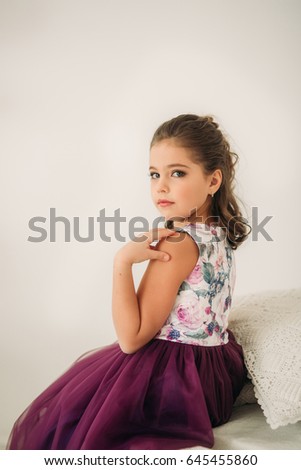 Beautiful girl in a purple dress and flower blouse posing for a photographer.