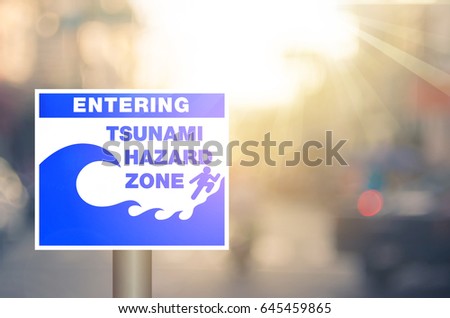 Tsunami hazard zone warning sign on blur traffic road with colorful bokeh light abstract background. Copy space of transportation and travel concept. Retro tone filter color style.