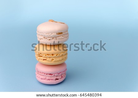 Picture of three sweet colorful macaroons on blue table background.