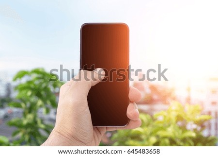 Man uses his Mobile Phone at cityscape background in morning light, close up, capture the moment by a smart phone in my hands. nature and cityscape background. building background.