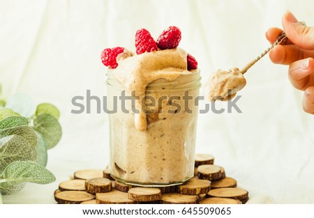 Melts raw vegan chocolate banana ice cream with raspberries in a glass jar eating spoon beautiful woman. Healthy vegetarian meal concept. Royalty-Free Stock Photo #645509065