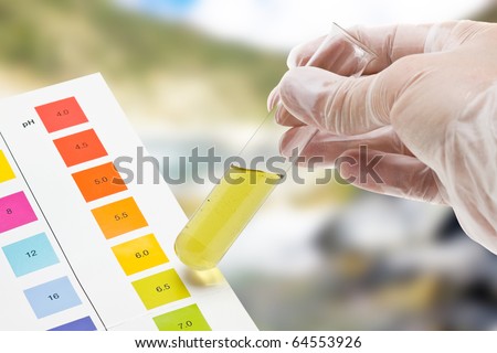 Hand holding test tube with pH indicator comparing color to scale Royalty-Free Stock Photo #64553926