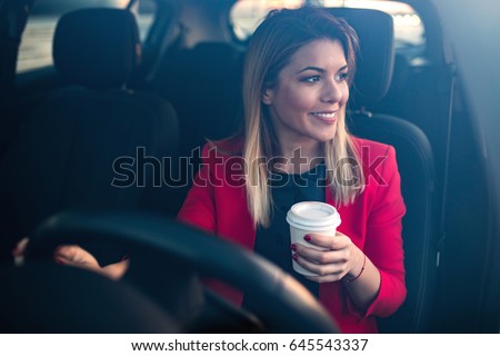 Woman sipping a coffee while driving a car. Royalty-Free Stock Photo #645543337