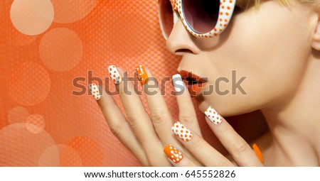 White orange manicure and makeup with a design of dots on female hand close up. Royalty-Free Stock Photo #645552826
