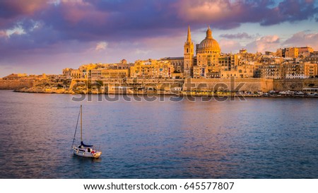Valletta, Malta - St.Paul's Cathedral in golden hour at Malta's capital city Valletta with sailboat and beautiful colorful sky and clouds