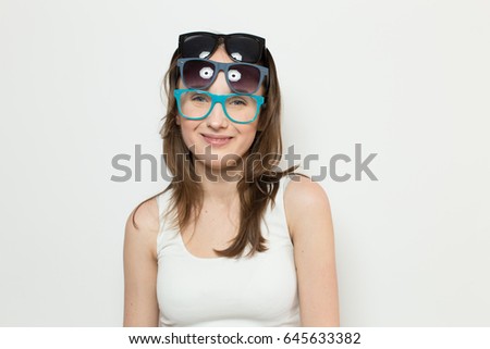 woman wearing 3 pairs of glasses together,
beautiful girl fooling around at camera with glasses
