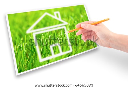 Hand of a girl with a pencil drawing a house of dream against the green grass.