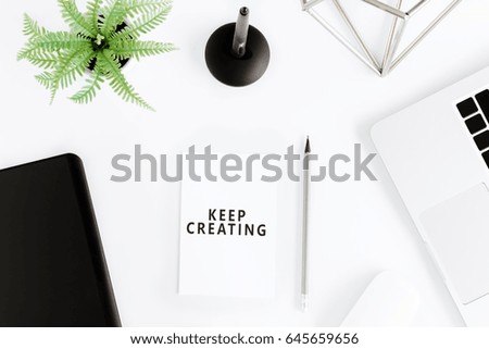 Top view of keep creating motivational quote and laptop at workplace