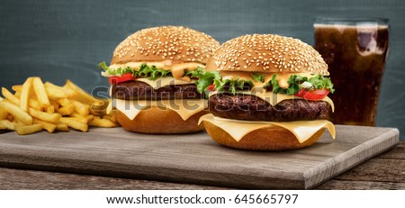 Two craft beef burgers on wooden table on blue background. Royalty-Free Stock Photo #645665797