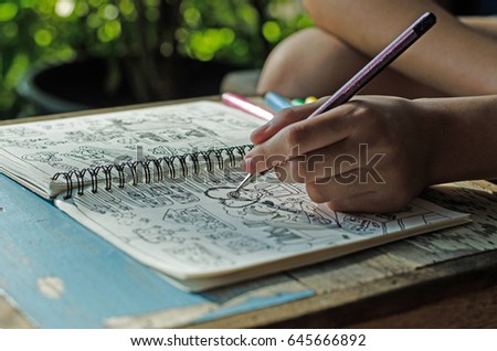 hands drawing cartoon and doodle on notebook diary for hobby in spare time