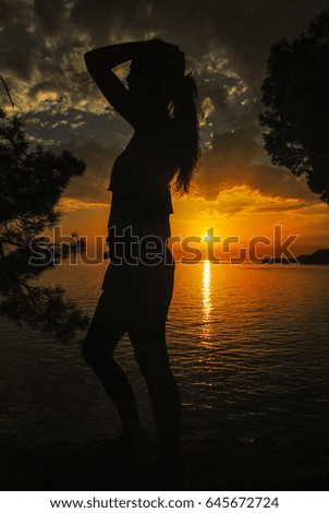 Woman silhouette in beautiful sunset sky and water colors