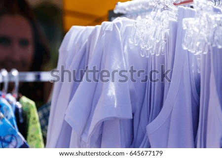 Baby clothes pants t-shirts sweaters shirts hanging on hangers in a shop outside in sunny weather