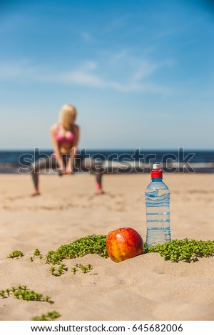By the sea sand ordered a bottle of water and apple - background gymnastics woman