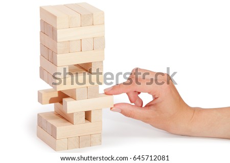 The tower from wooden blocks and man's hand take one block Royalty-Free Stock Photo #645712081